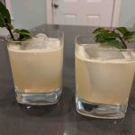 Two cocktails in rocks glasses with ice cubes, garnished with fresh mint sprigs.