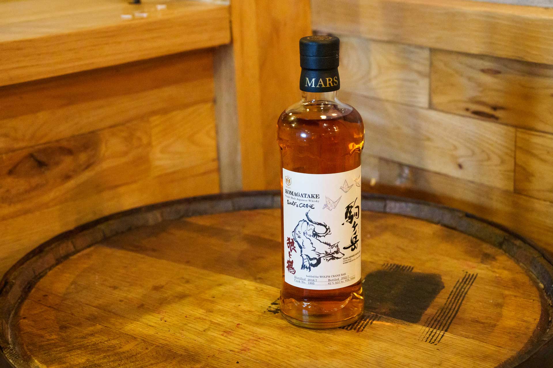 Wolf & Crane bottle above a barrel showing the Japanese Whisky